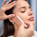 beautician is preparing client's face for procedure