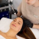 woman receiving a facial treatment from a professional wearing black gloves